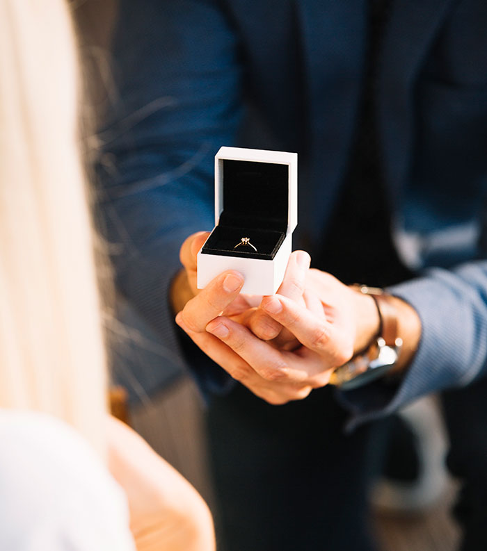 Man holding an open ring box with an engagement ring, illustrating some of the worst proposal stories.
