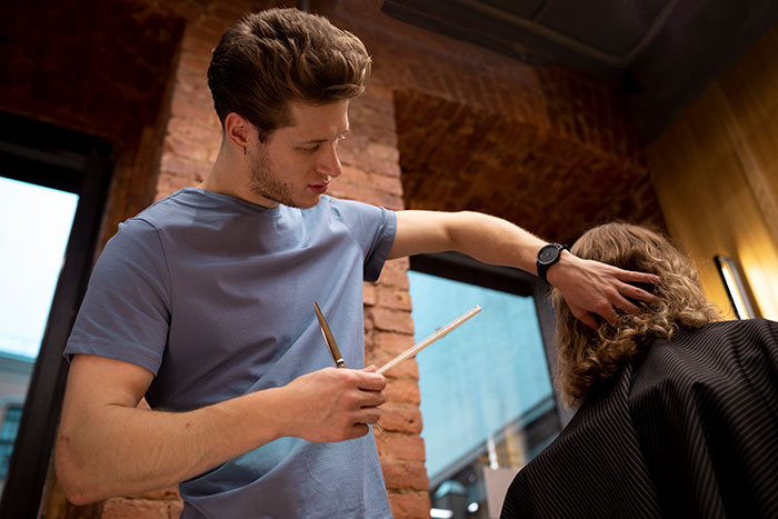 Man focused on hairstyling, holding scissors and comb, illustrating one of the worst proposal stories involving partners.