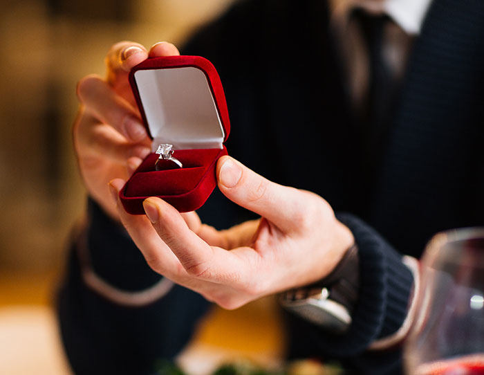 Person holding a red ring box with an engagement ring, illustrating a worst proposal story moment.