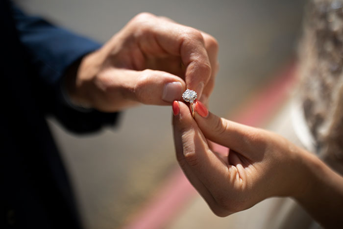 Close-up of a person holding an engagement ring, illustrating worst proposal stories that might make you side-eye your partner.
