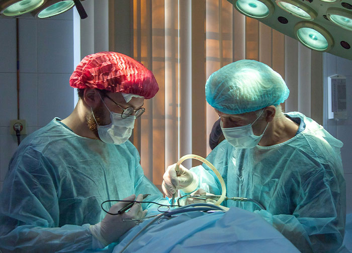 Two surgeons in protective gear performing a complex surgery, highlighting worst patient experiences in hospital care.