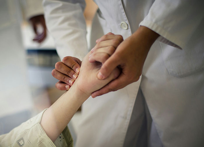 Doctor holding a patient's hand in a hospital setting illustrating worst things patients had to endure.