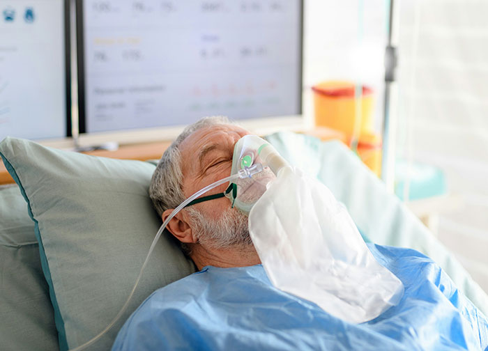 Elderly male patient in hospital bed wearing oxygen mask, representing worst things patients endure in healthcare settings.