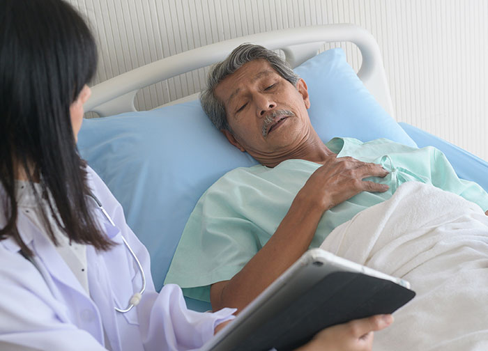 Elderly patient in hospital bed with nurse, illustrating some of the worst things patients endure in healthcare settings.