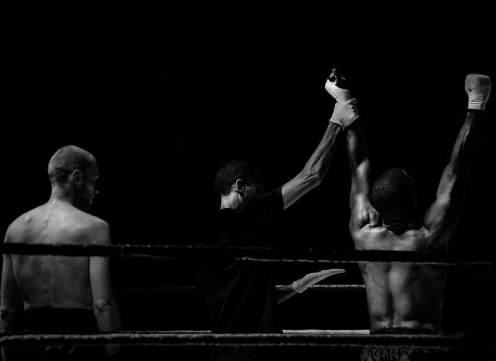 Boxer raising arms in victory with referee between two fighters, symbolizing tough dilemmas like public speaking or deep water.