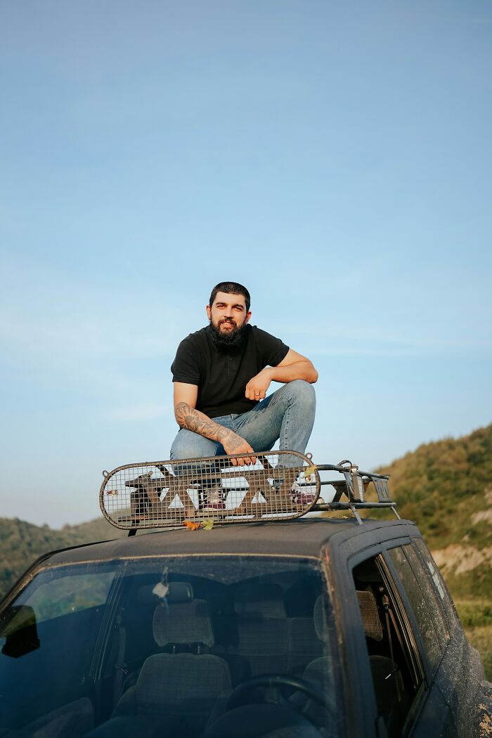 Man with beard and tattoos sitting on off-road vehicle roof, representing incredible minds who proved you don’t need a degree to be a genius.