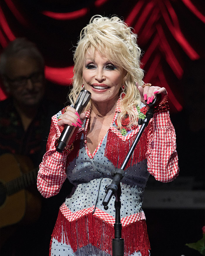 Female star speaking on stage with microphone, highlighting trends of nannies and the internet in childfree decisions.