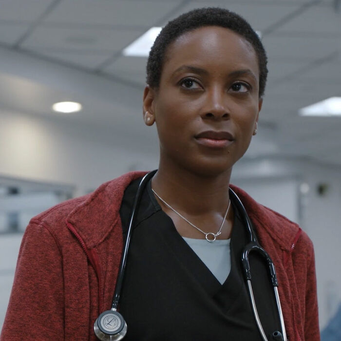 Close-up of Dr. Heather Collins wearing a stethoscope and red jacket in a hospital setting from The Pitt season 2.