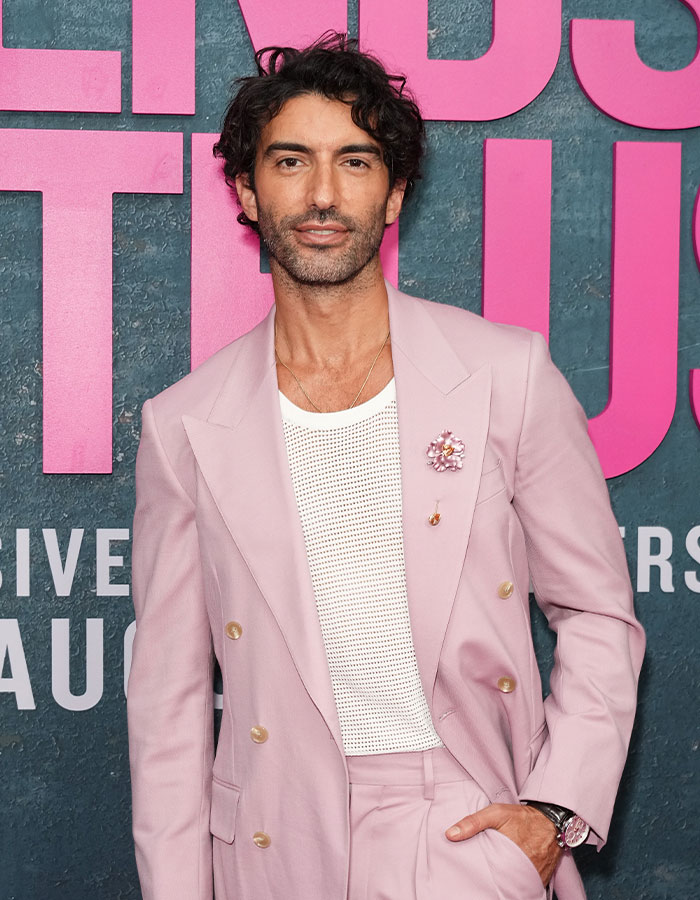Justin Baldoni posing in a light pink suit at an event, related to disturbing comments exposed during testimony.