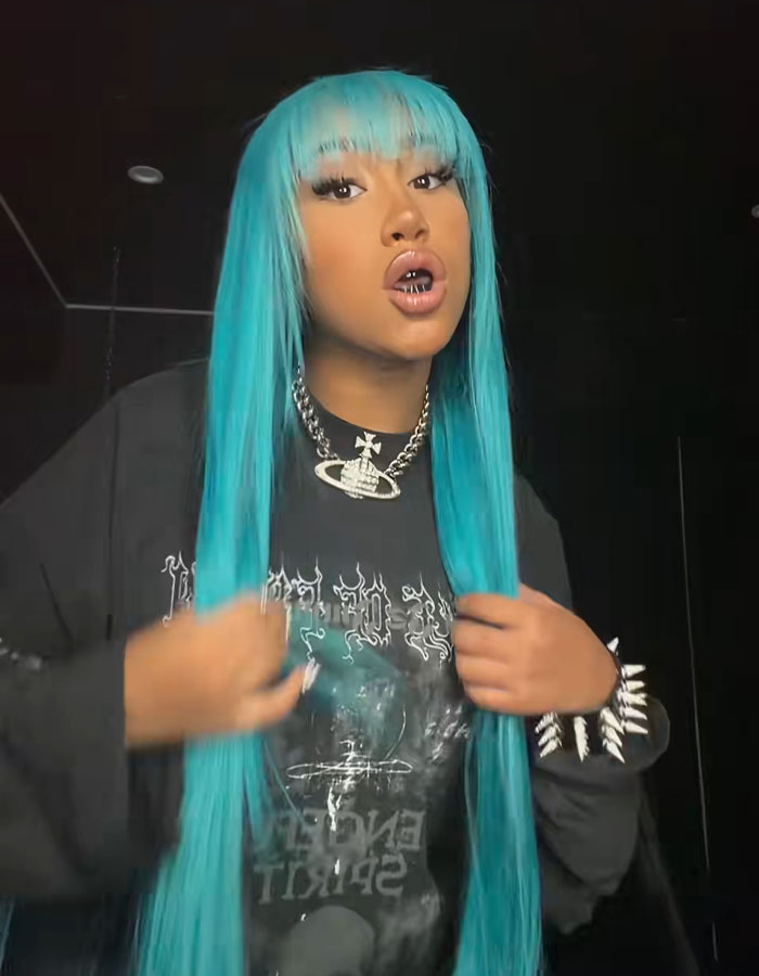Person with long blue hair and black graphic shirt posing indoors, related to Kim Kardashian crashing North West livestream viral moment.