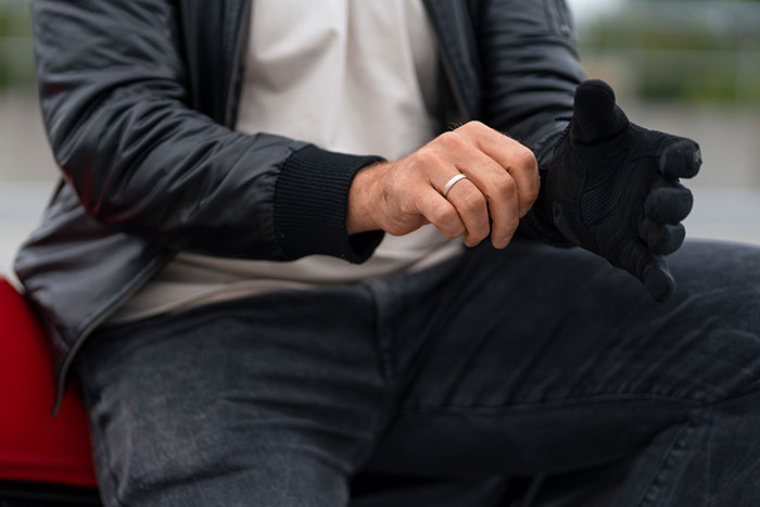 Man wearing a wedding ring on his left hand while putting on a black glove, symbolizing a widower boyfriend scenario.