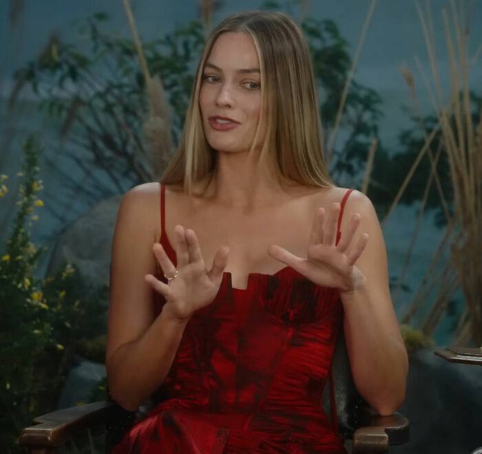 Margot Robbie in a red dress discussing her on-set relationship with Wuthering Heights co-star Jacob Elordi during an interview.