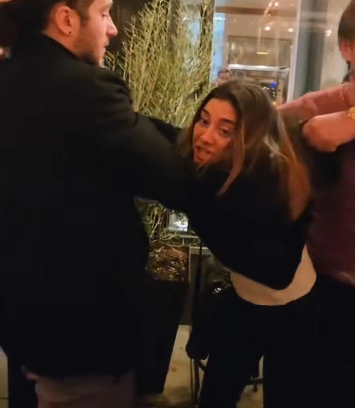 Woman being restrained by men in a tense altercation outside, related to SF bartender viral response incident.