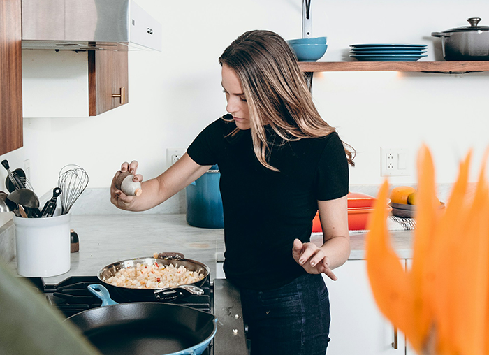 Young woman cooking in a modern kitchen, focusing on preparing food amid concerns about boyfriend fears golddiggers.