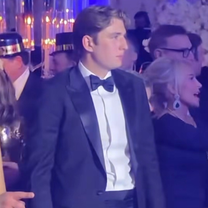 Barron Trump in a tuxedo at a New Year's Eve party, sparking paternity conspiracy theories in a crowded, dimly lit venue. Barron Trump in a tuxedo at a New Year's Eve party, sparking paternity conspiracy theories in a crowded, dimly lit venue.
