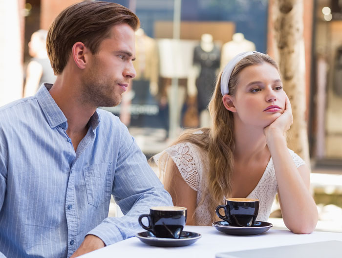 Couple at cafe, woman bored and man concerned over coffee — deal breakers dating