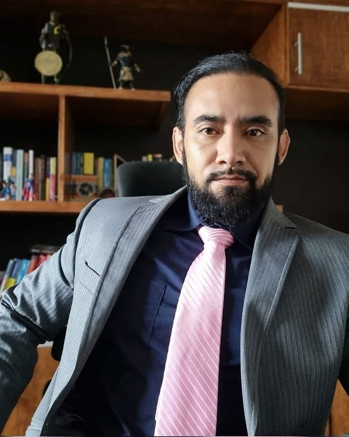 Man in gray suit and pink tie sitting confidently in office setting illustrating gender identity and child support topics.