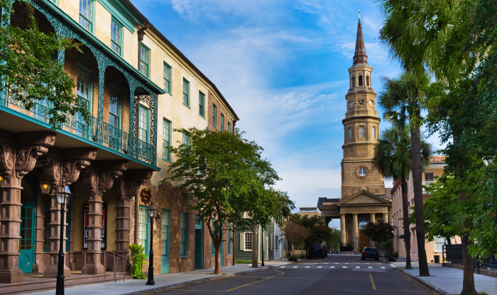 Historic street with old buildings and a church tower under blue sky in a famously haunted American town.