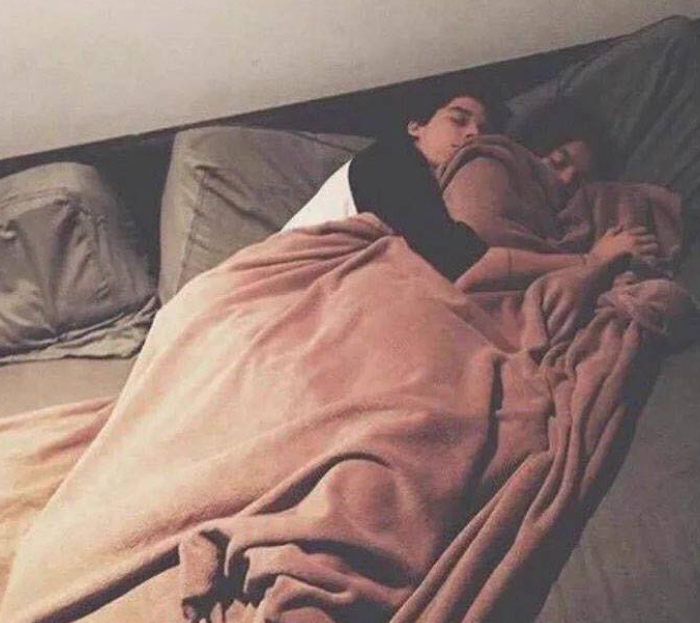 A couple lying asleep in bed under a blanket, illustrating sleep differences between women and men.