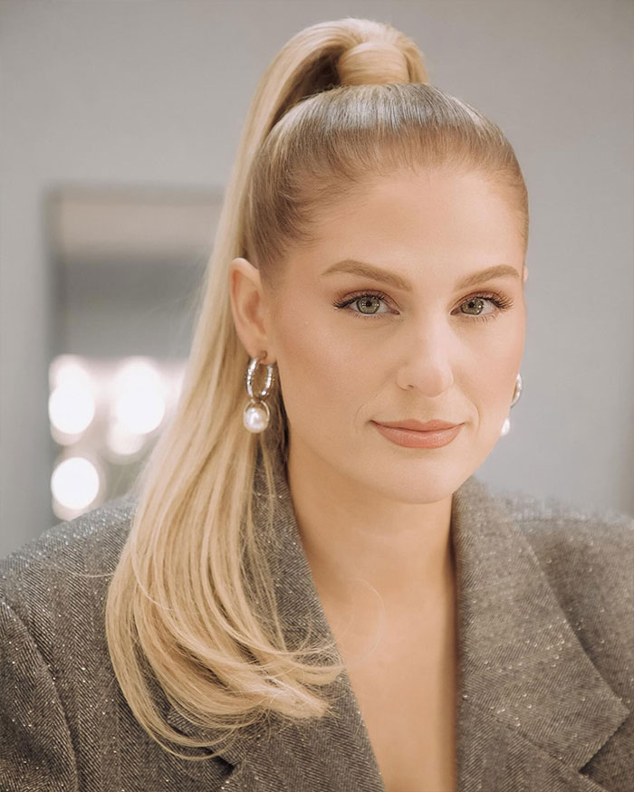 Meghan Trainor with a high ponytail and pearl earrings, addressing backlash and surrogate use for her baby. Meghan Trainor with a high ponytail and pearl earrings, addressing backlash and surrogate use for her baby.