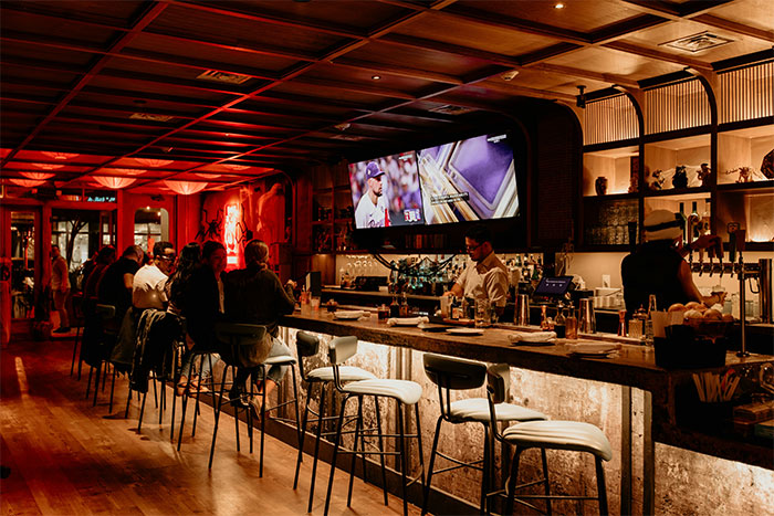 Bar interior with people sitting at the bar counter under warm lighting, illustrating social interaction after work hours.