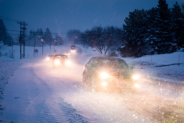 Cars driving through a snowy road at dusk with headlights on, illustrating the dad accused by his own kids in harsh conditions.