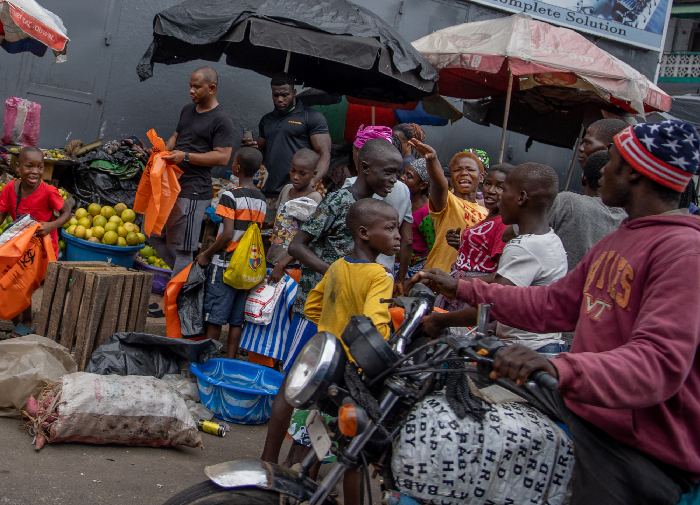 Crowded market with vendors, children and a motorcycle, illustrating stressful countries urban life