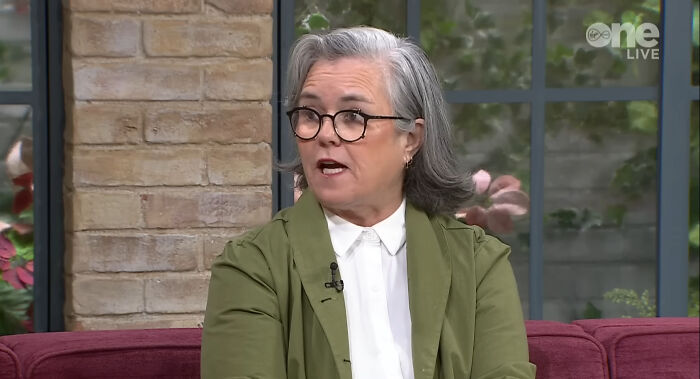 Woman with gray hair and glasses speaking during a live interview about people meeting their idols in real life regret.