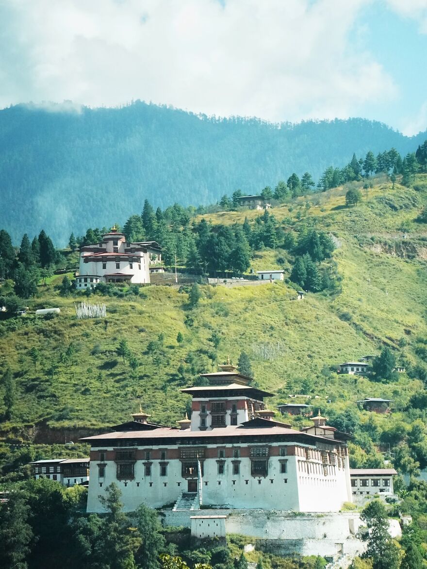Traditional Bhutanese buildings surrounded by green hills and trees, highlighting nations setting new global standard for paid leave.