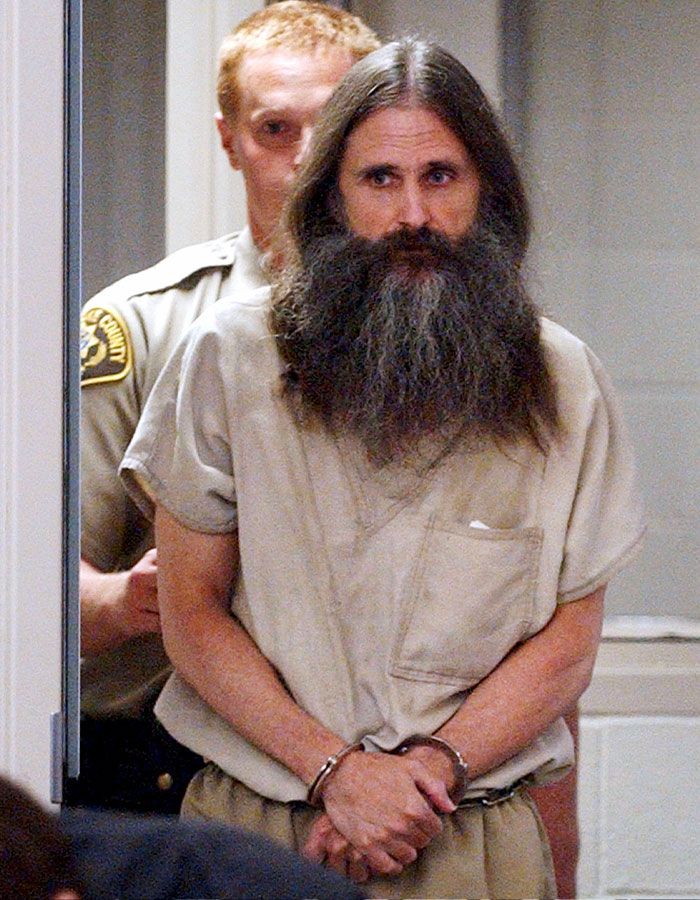 Man with long beard and handcuffs escorted by law enforcement, illustrating biggest bombshells in Elizabeth Smart Netflix documentary.