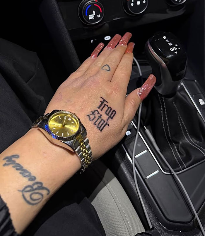 Close-up of a hand with tragic tale of child stars tattoo near a car gear shift and wristwatch, highlighting Amanda Bynes&rsquo; new ink.