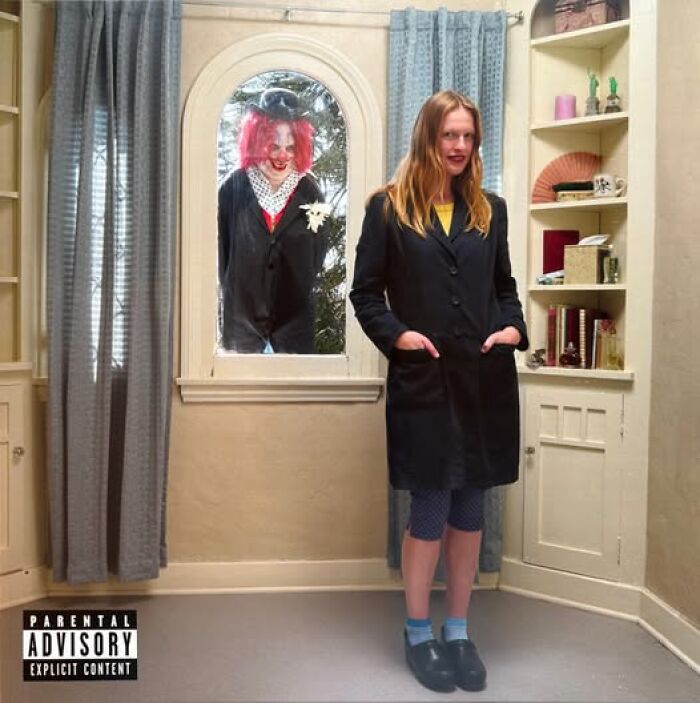 Woman standing inside a room with a creepy clown outside the window, showcasing a hilariously bad album cover design.