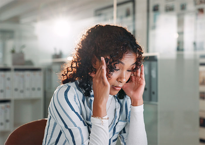 Woman frustrated at work, holding her head in her hands, illustrating stress related to coworker disability claims.