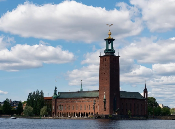 Historic building by waterfront under blue sky, representing best countries to raise a family with high child wellbeing.