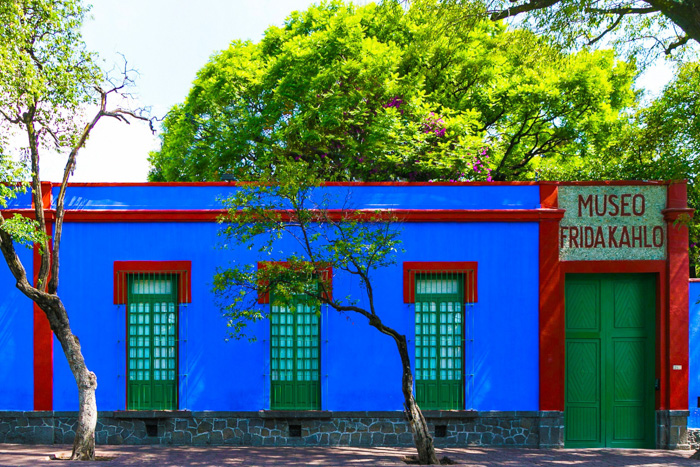 Bright blue Frida Kahlo Museum facade with green doors and trees, for fun facts about Mexico