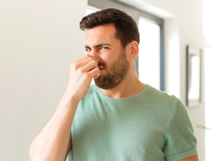 Bearded man pinching his nose in disgust, representing dating deal-breakers