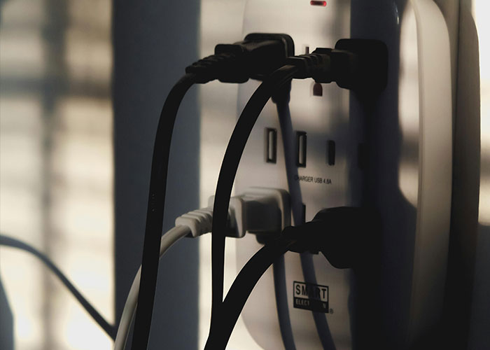Close-up of multiple electrical cords plugged into a smart power strip representing neurodivergent habits concept.