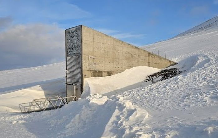 Concrete structure partially buried in snow on a remote, forbidden place on Earth with clear blue sky above.