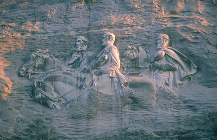 Stone carving of three historic figures on horseback, representing heritage of some of the oldest countries in the world.
