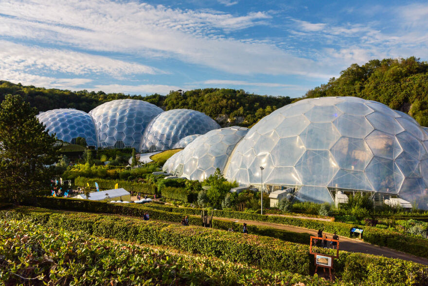 The Eden Project in nature-inspired geodesic domes surrounded by greenery under a vibrant blue sky.