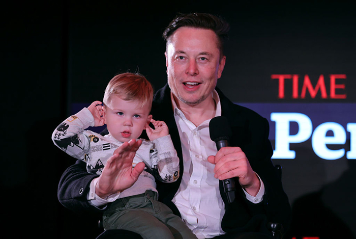 Elon Musk holding one of his 14 children, highlighting complex relationships spanning five mothers over two decades.