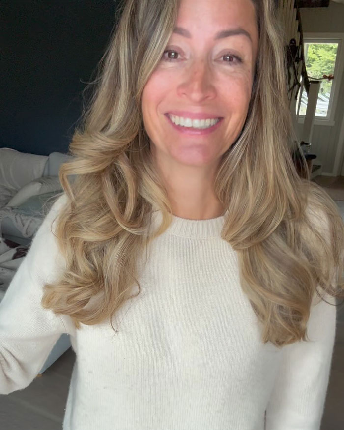 Woman with long blonde hair smiling indoors, related to David Beckham&rsquo;s ex-assistant reacting to Brooklyn Beckham family rift.