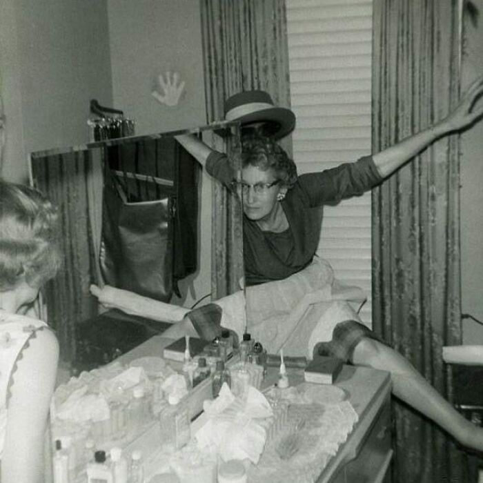 Woman appearing to float and stretch oddly behind a mirror in an old black and white creepy and odd vintage photo.
