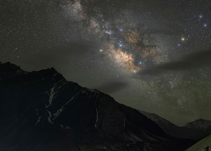 Starry night sky over dark mountainous landscape illustrating wacky stories told by 51 people hoping to be believed.
