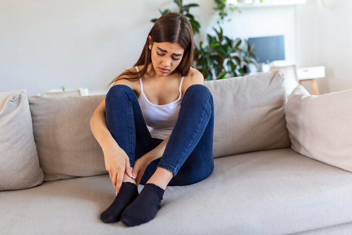 Young woman sitting on a couch looking distressed, capturing moments that hit people harder than expected.