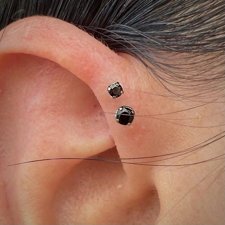 Close-up of ear showcasing two black stud earrings highlighting popular types of ear piercing styles.