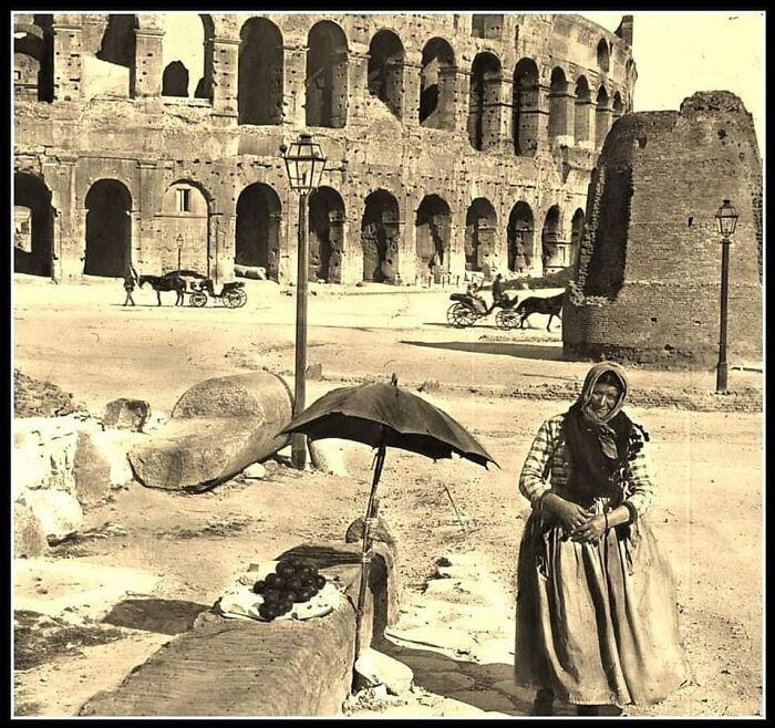 Woman selling fruit near the ancient Colosseum ruins, capturing a historic moment in the sad beautiful history of humanity.