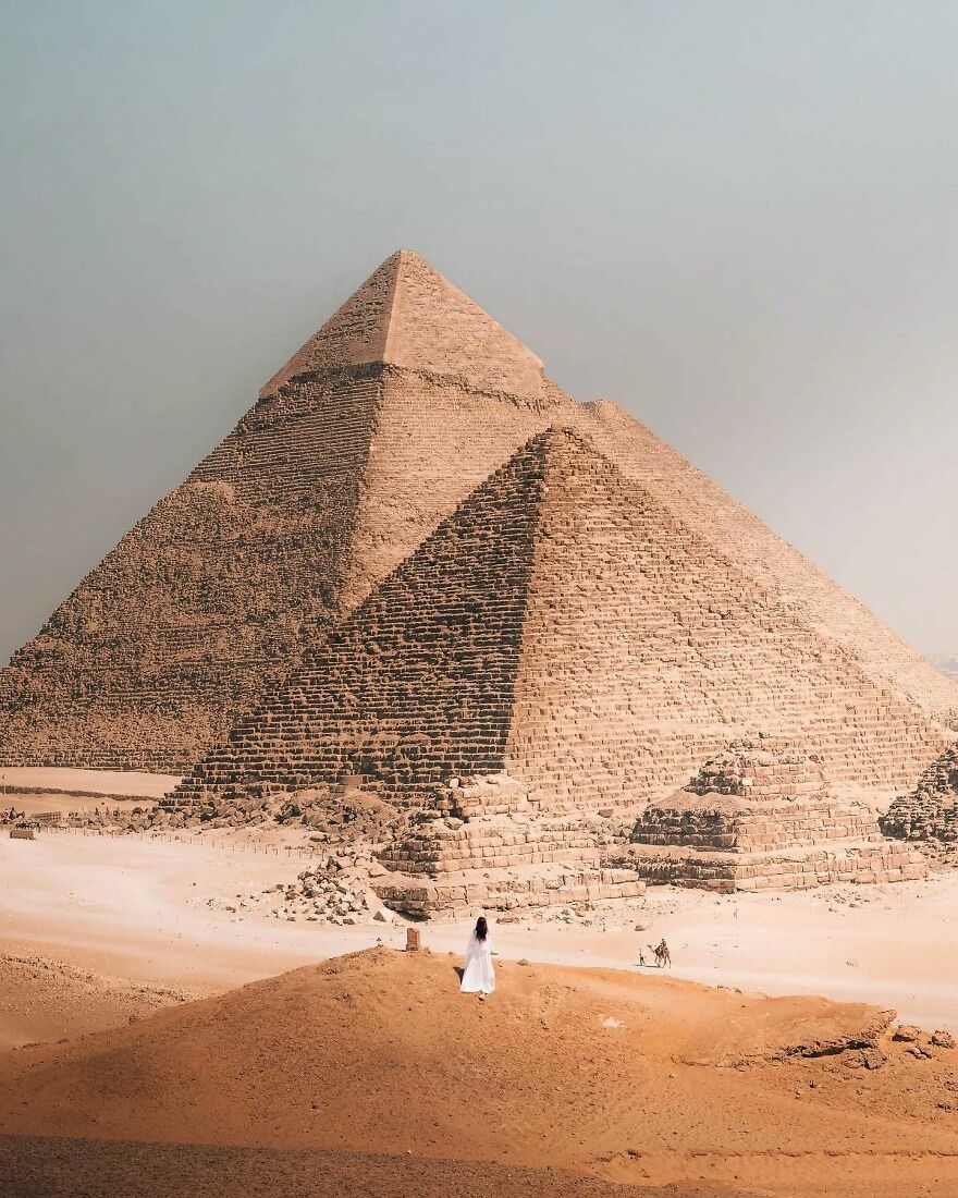 Ancient pyramids in Egypt with a person in white walking nearby, a must-see place you should visit at least once.