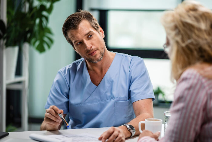 Man in blue scrubs discussing misconceptions about life in prison with a woman during a counseling session.
