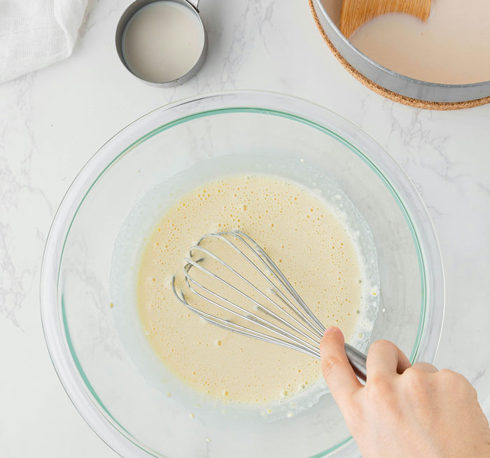 Hand whisking batter in a glass bowl on marble counter, people realized friends or family were very weird